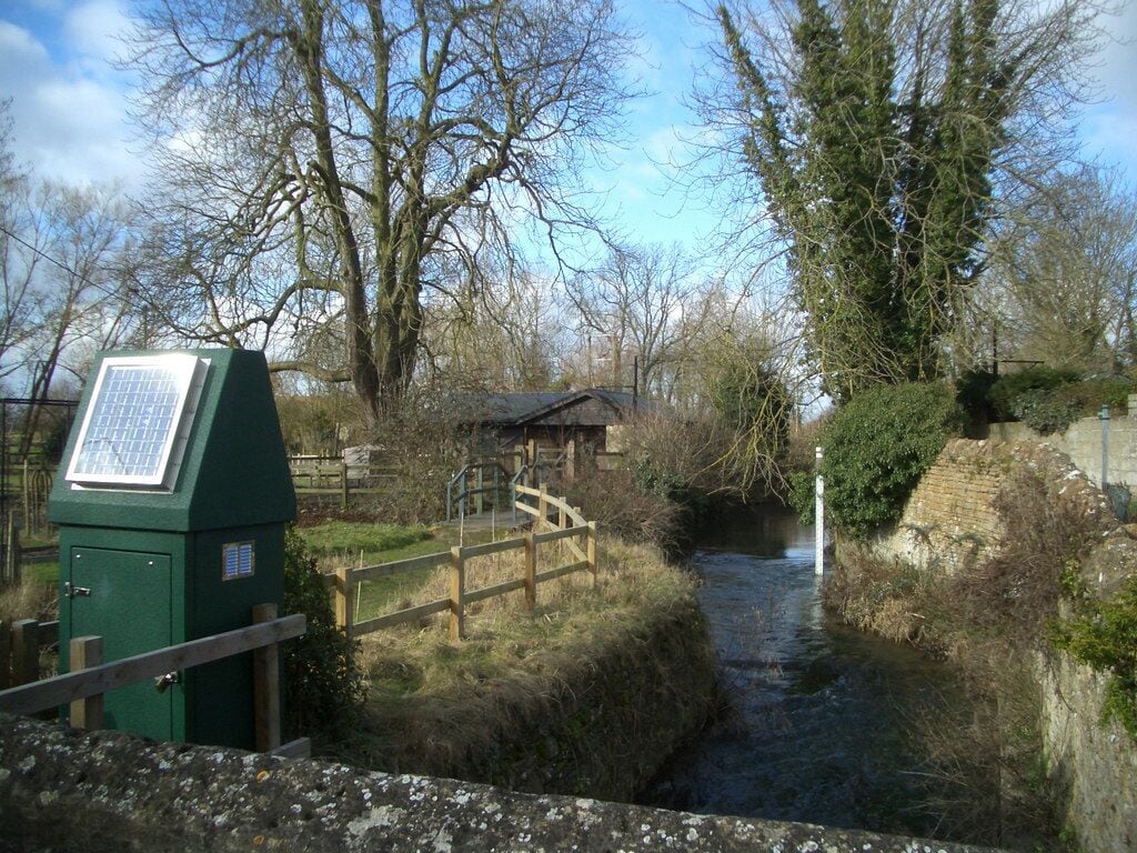 Bampton Flood Warning Station This is the Environment Agency's flood warning site on the Highmoor Brook in Bampton, a river which has flooded properties in this part of town on several occasions. The equipment, solar powered of course, provides early warning of dangerously rising water levels.