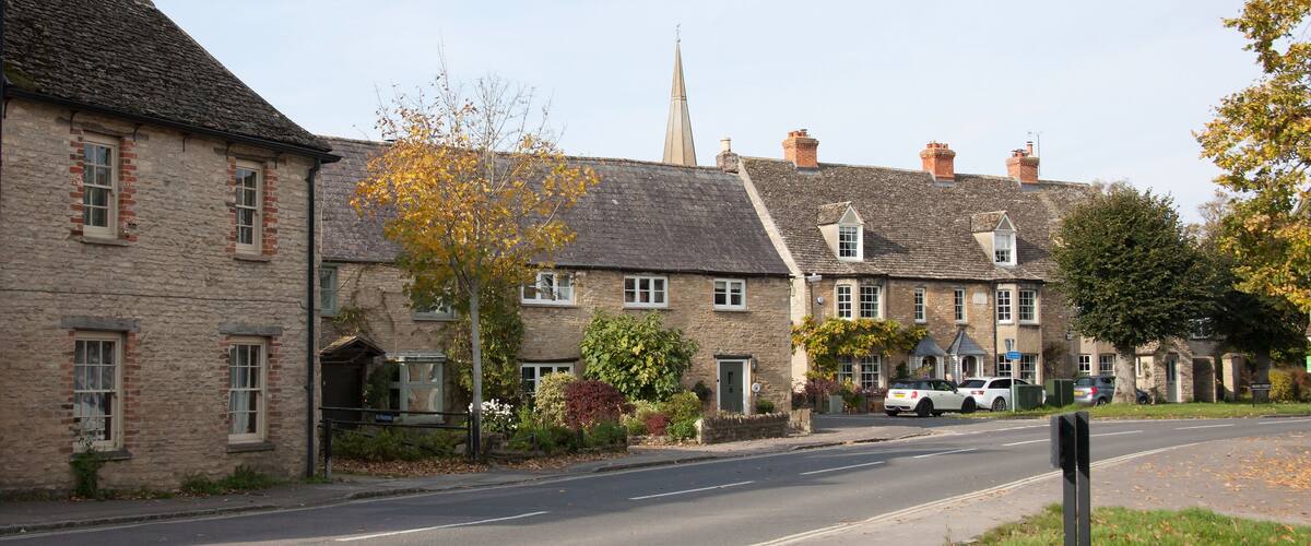 A row of stone houses with a church steeple in the background.