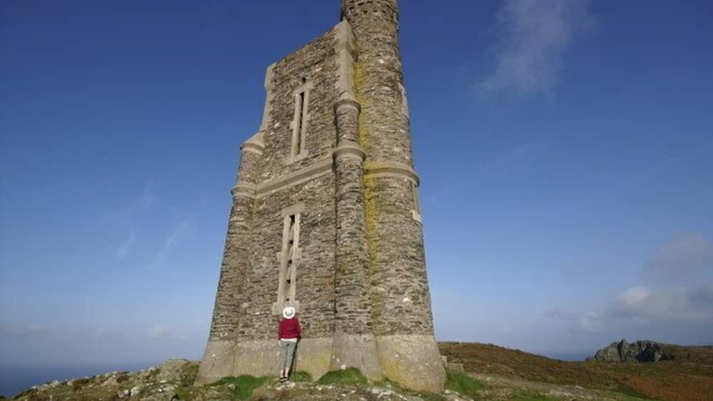 Ein hoher, alter Wehrturm, vor dem eine Person steht.