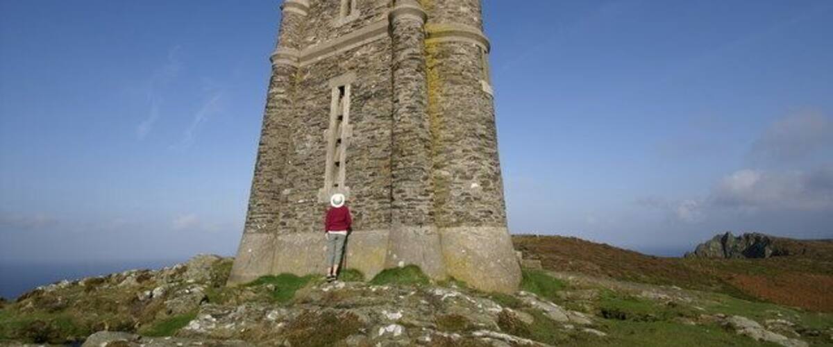 Una torre de piedra alta y antigua con una persona parada frente a ella.