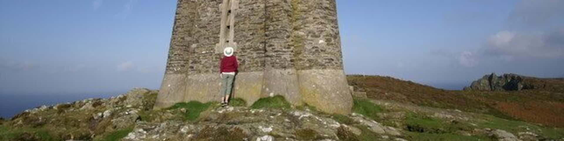A tall, ancient stone tower with a person standing in front of it.
