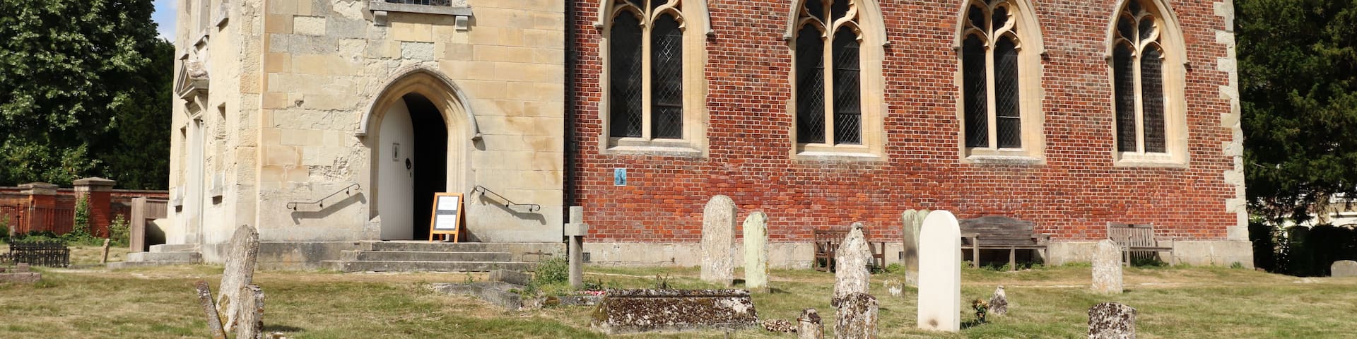 A church with a bell tower, arched windows, and a graveyard in front.