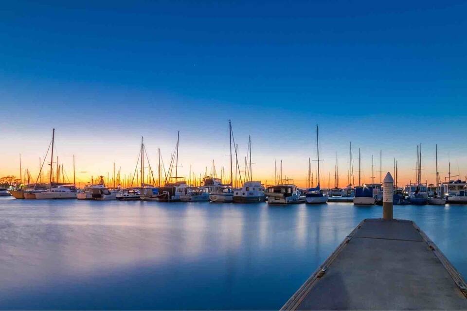 Un port esportiu al capvespre amb nombrosos velers amarrats.
