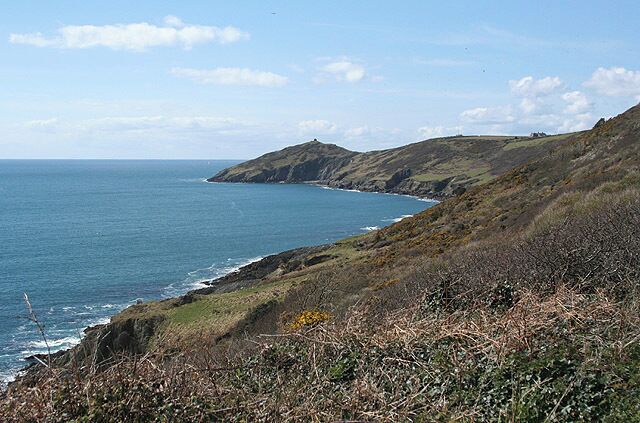 A coastal landscape with rolling hills and a clear view of the ocean.