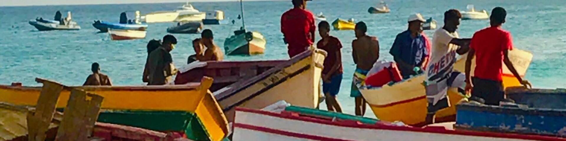 A row of small boats docked at a pier with people standing on them.