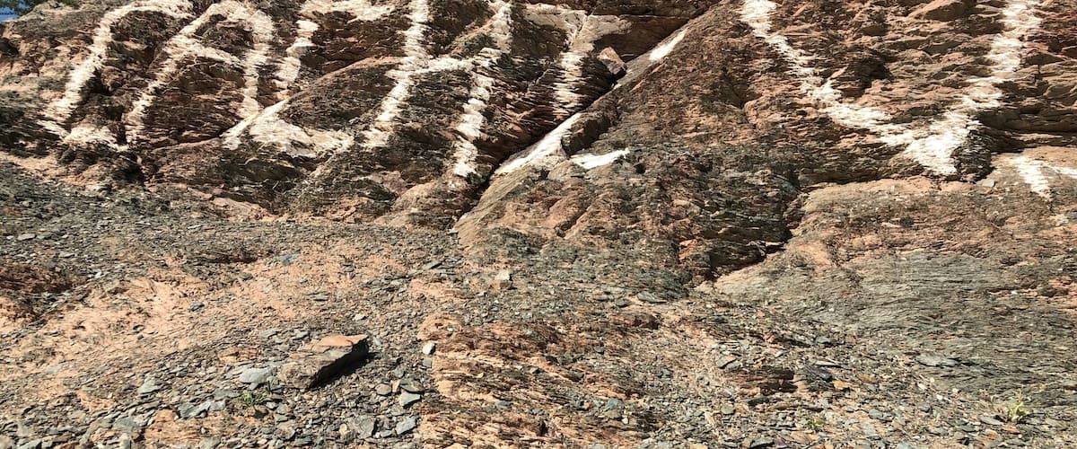 A rocky landscape with a heart-shaped carving and a cross on a hill.
