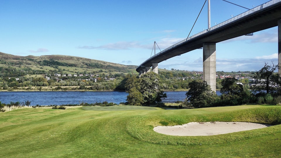 A golf course with a bridge in the background.