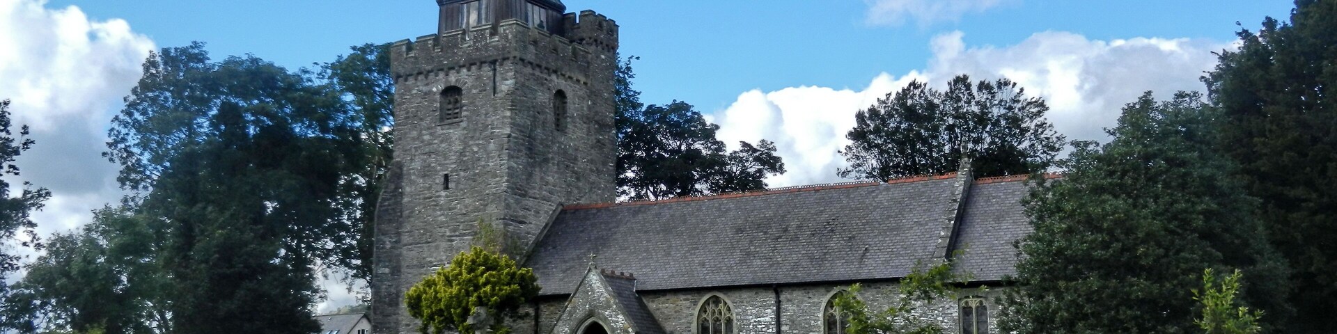 A historic church with a tall tower and a stone wall in front.