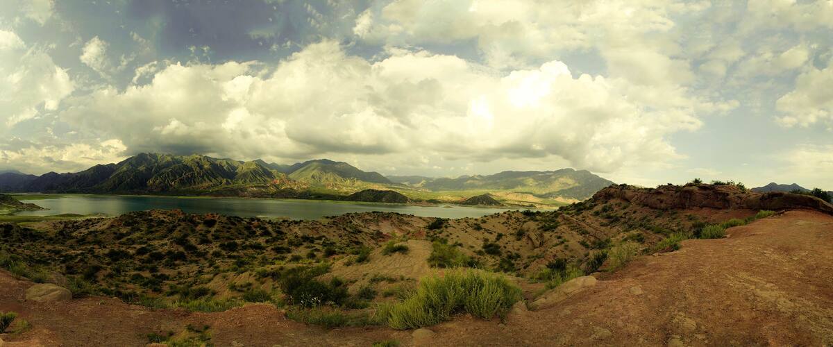 A mountainous landscape with a lake and scattered vegetation.