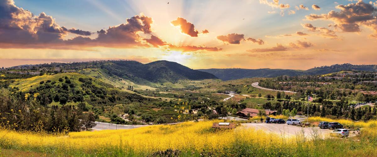A valley with a winding road, a small settlement, and a mountain in the background.
