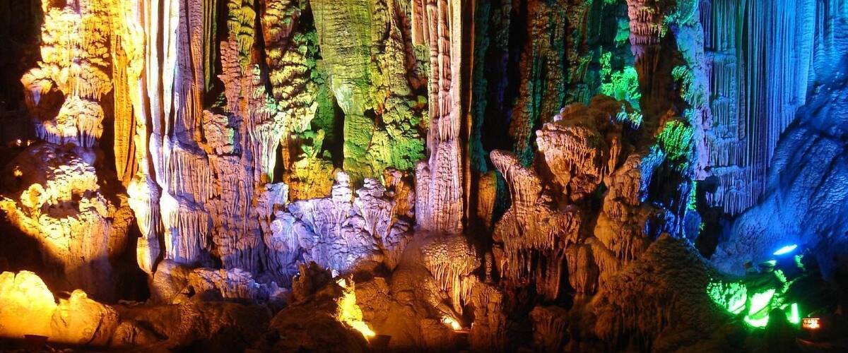 A cave with colorful illuminated stalactites and stalagmites.
