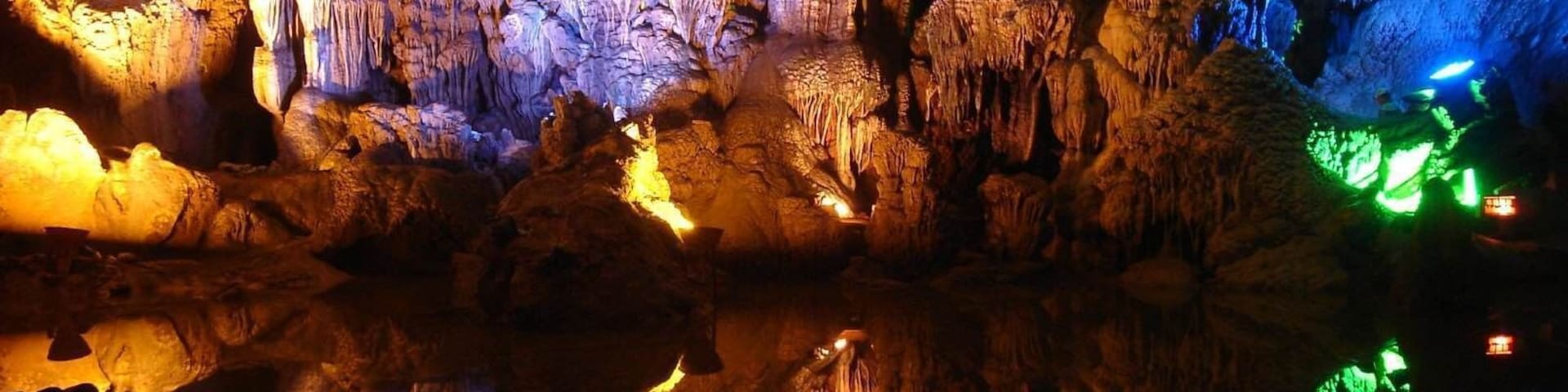 A cave with colorful illuminated stalactites and stalagmites.