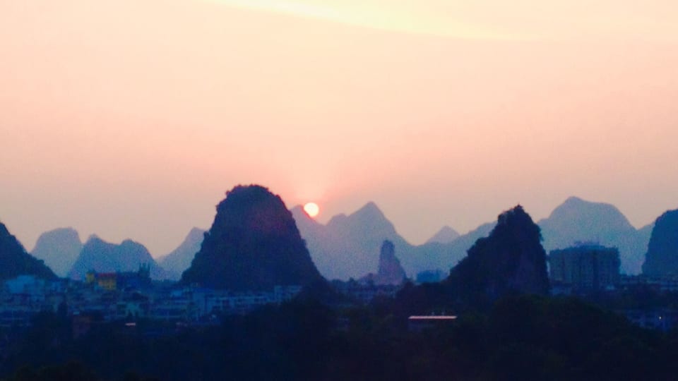 Atardecer sobre un paisaje montañoso con un río en primer plano.