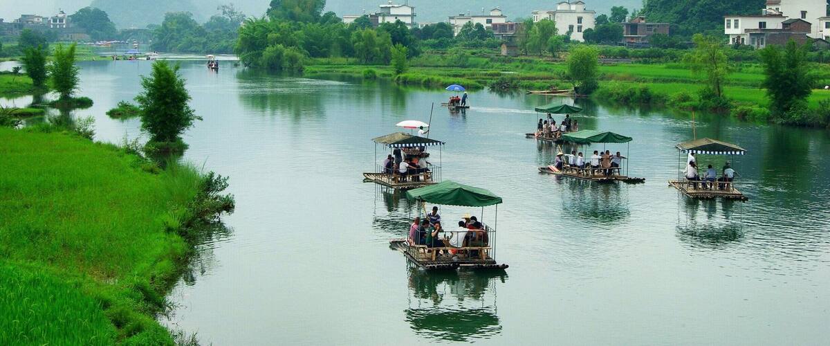 A river with boats, greenery, and distant mountains.