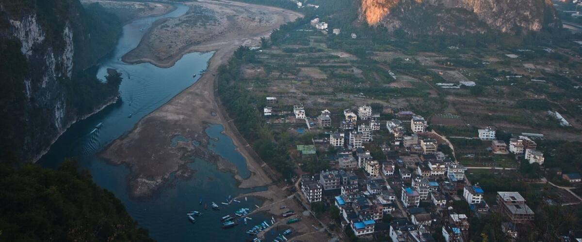 A river winding through a valley with a town and mountains in the background.