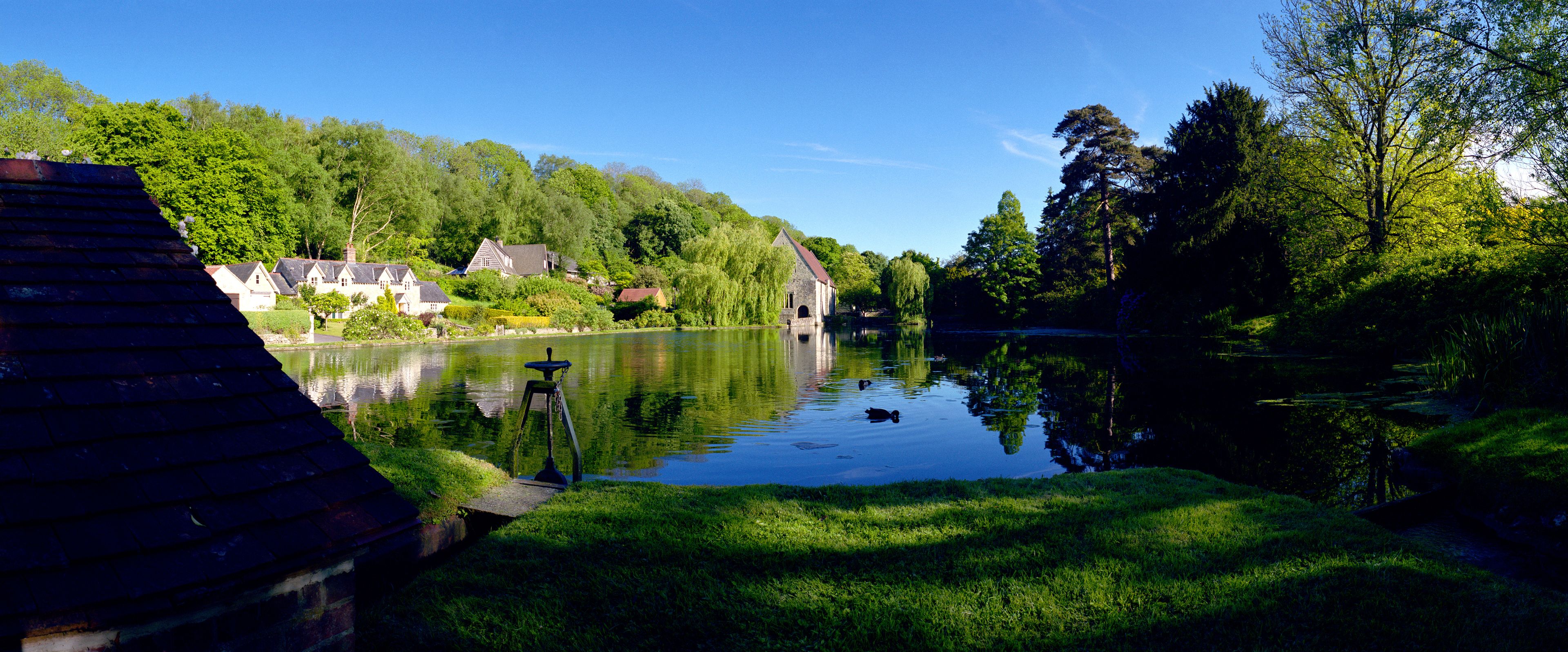 Un río tranquilo con un muelle de madera, abundante vegetación y casas tradicionales a lo largo de la orilla.