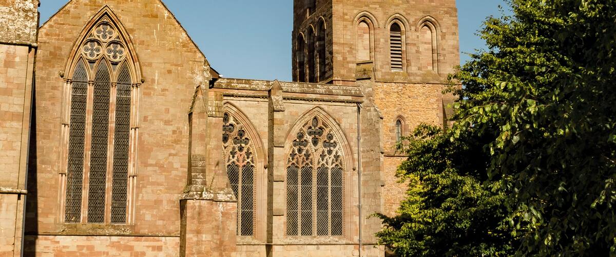 Een kerk met een hoge spits en boogvensters.