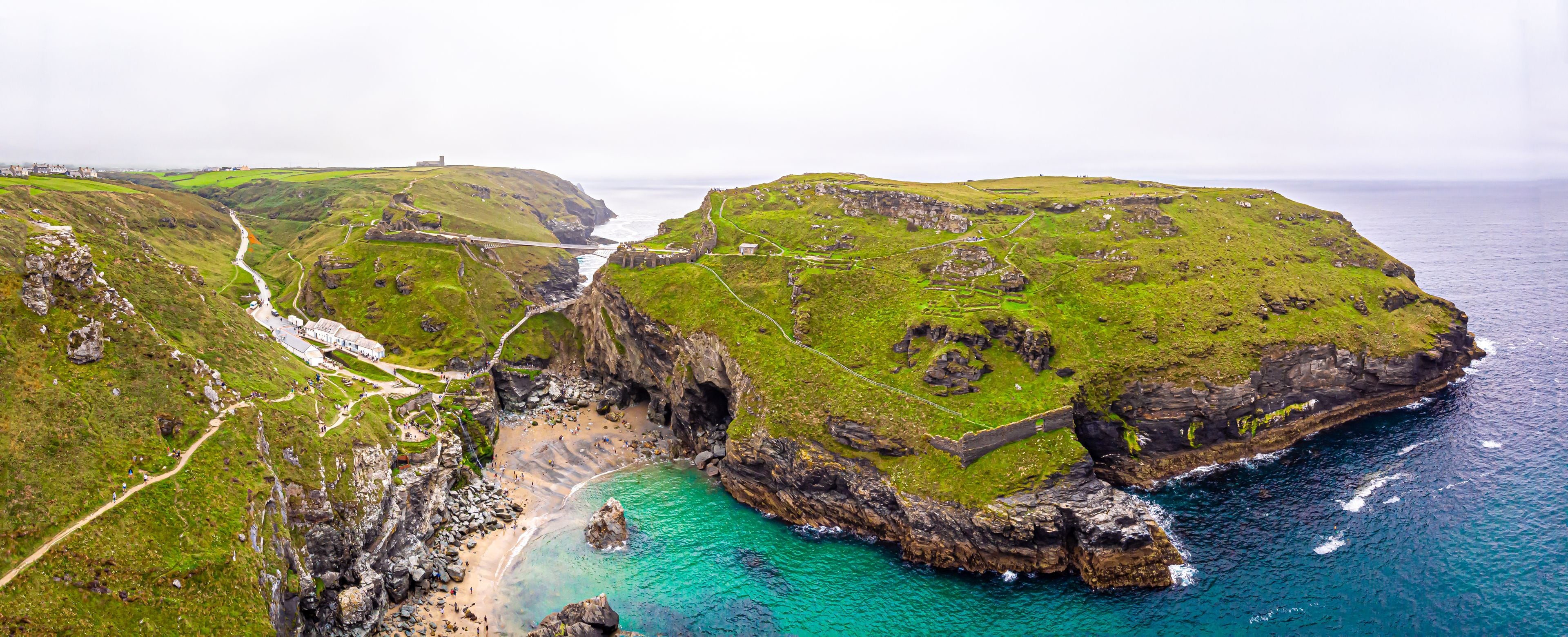 A coastal landscape with a bridge, cliffs, and a beach.