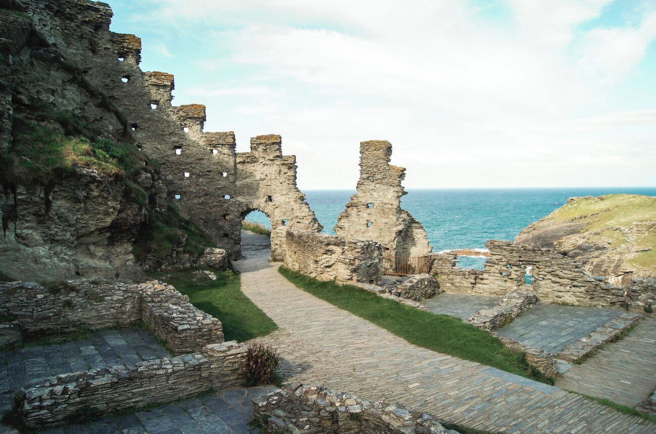 Ancient stone ruins with arches and a pathway leading to the sea.