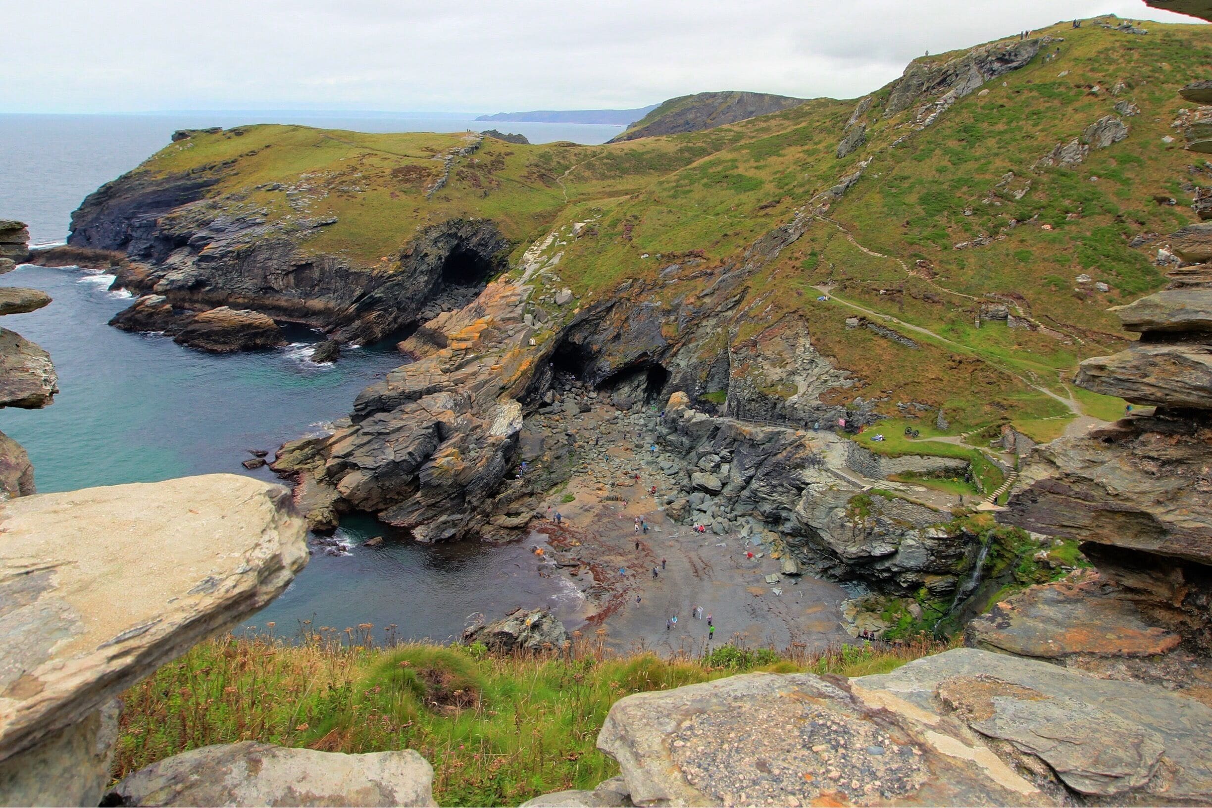A rugged coastline with rocky cliffs, grassy hills, and a sea view.