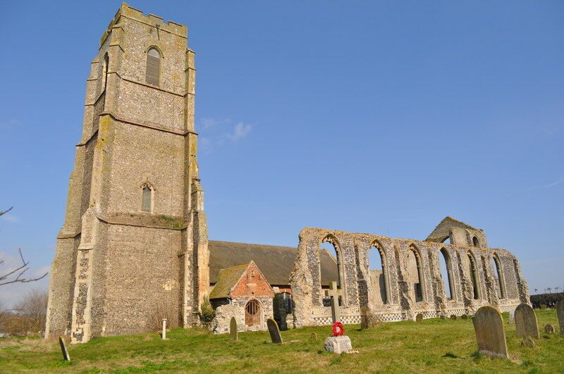 An old church with a tall bell tower and a ruined nave.