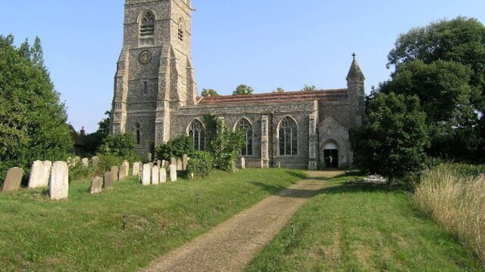 A historic church with a tall tower and arched windows, surrounded by a cemetery.