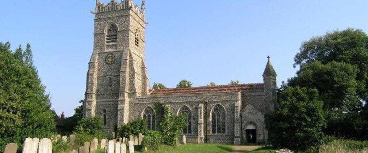 A historic church with a tall tower and arched windows, surrounded by a cemetery.