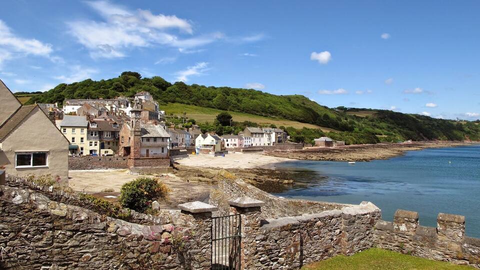 A coastal village with stone buildings, a beach, and a rocky shoreline.