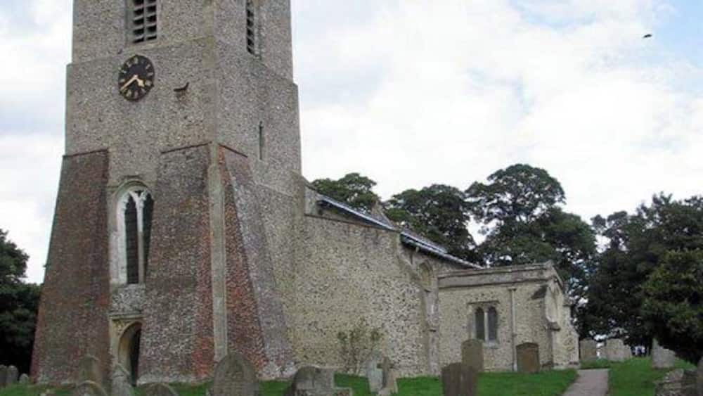 A church with a clock tower and a graveyard.