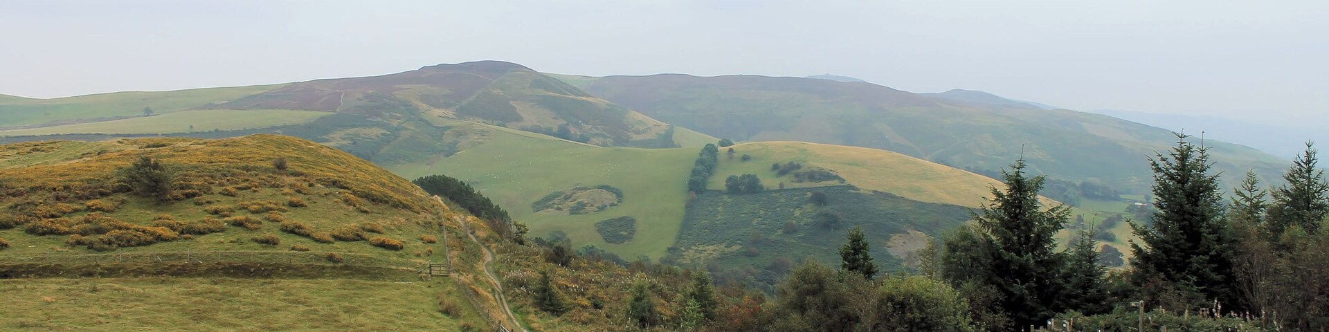 Entrance, with Moel Famau in the background. Penycloddiau Hill Fort, Clwydian Hills, North Wales. One of the largest hillforts in Wales, Penycloddiau is 21 hectares in area with its surrounding defending ditches nearly 2 km in length.