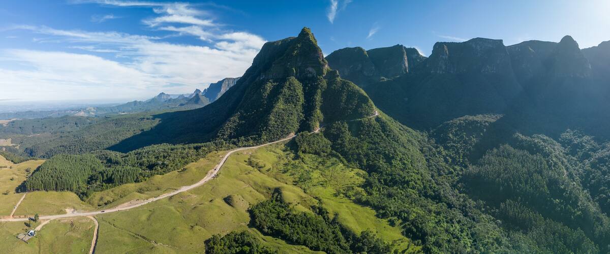 A mountainous landscape with a winding road and dense forest.