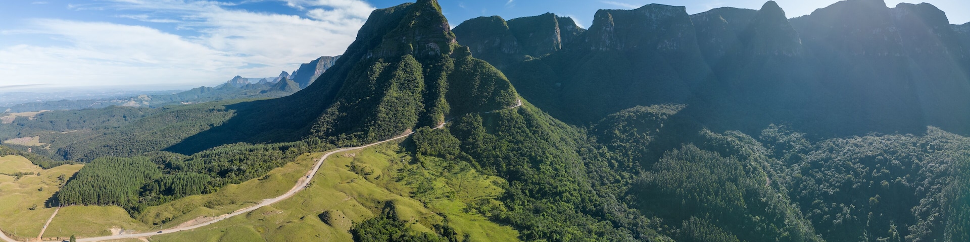 A mountainous landscape with a winding road and dense forest.