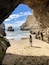 A beach with a cave entrance, rocky cliffs, and the ocean.