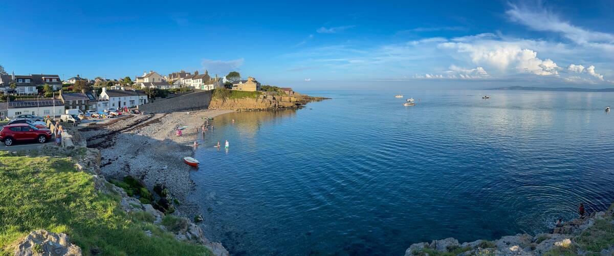 A coastal town with a rocky shoreline, boats on the water, and houses along the beach.