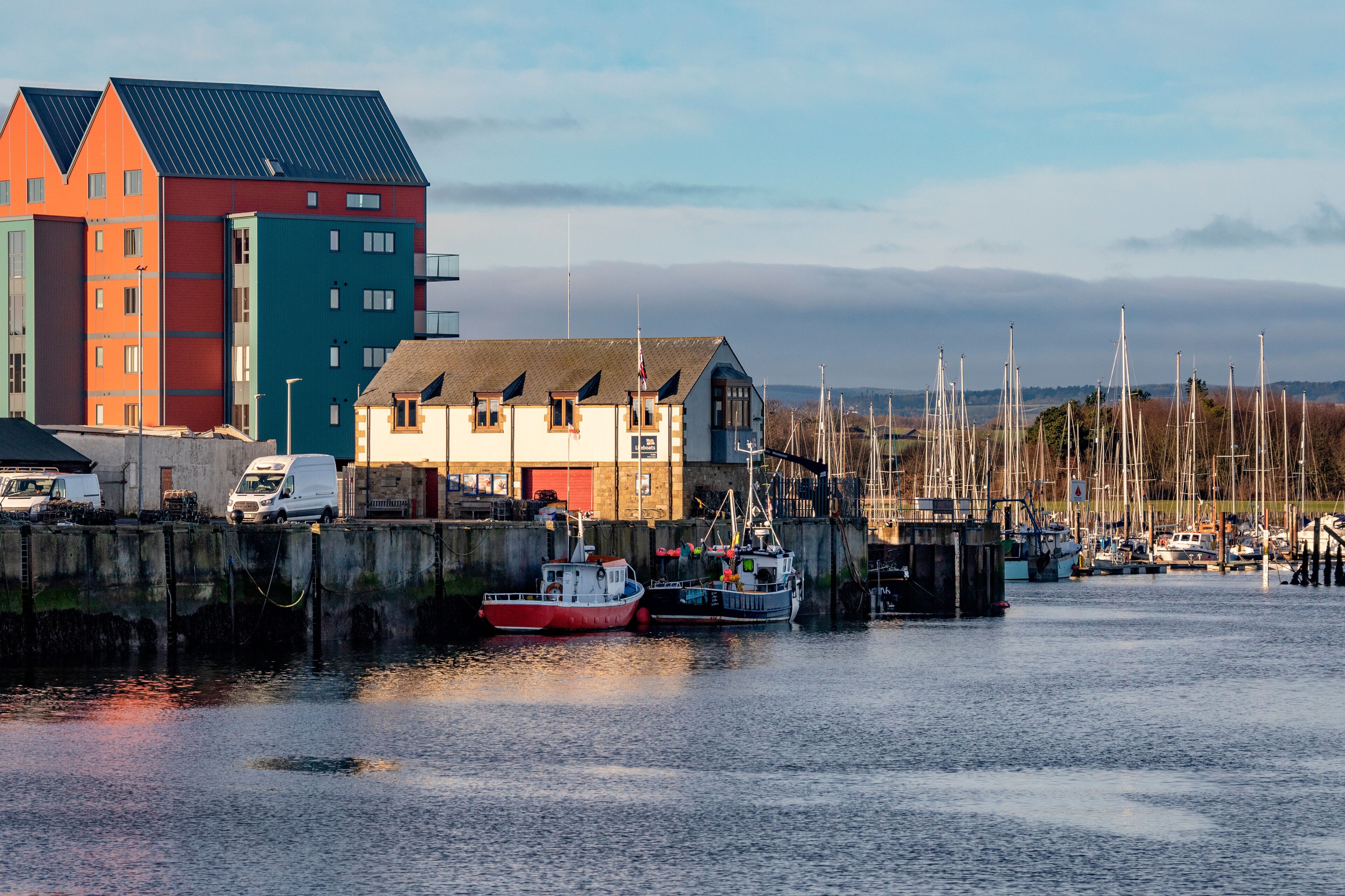 A harbor with colorful buildings, boats, and a distant view of mountains.