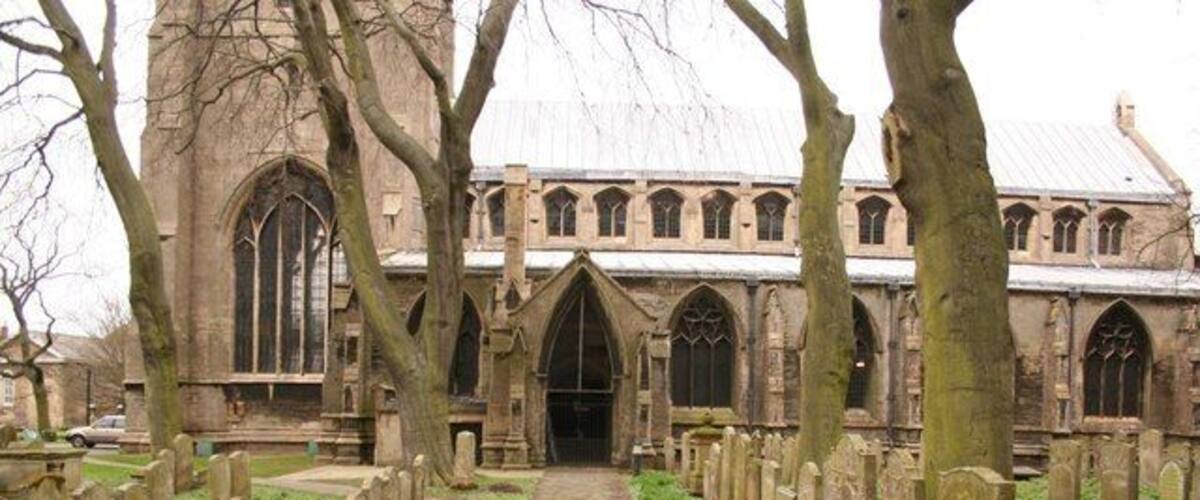 A church with a central aisle flanked by tombstones, surrounded by trees.