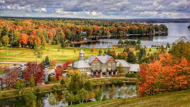 A lakeside resort with autumn foliage, a golf course, and a prominent building with a clock tower.