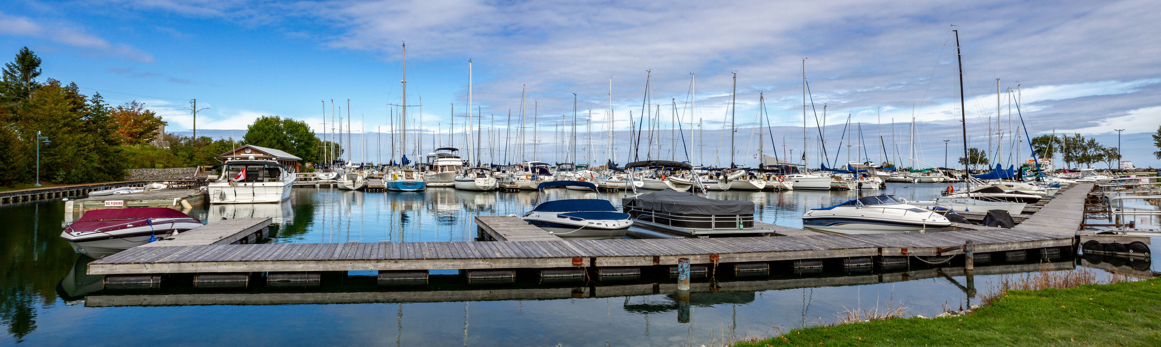 A marina with numerous sailboats docked at wooden piers.