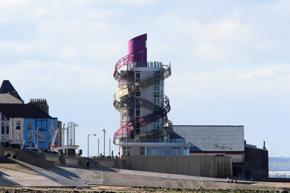 Un edificio costero con una escalera en espiral y un tejado rojo.