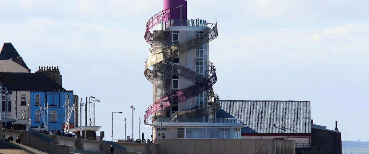 A coastal building with a spiral staircase and a red roof.