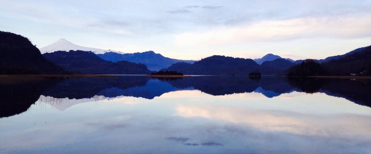 A calm lake reflecting mountains and a clear sky.