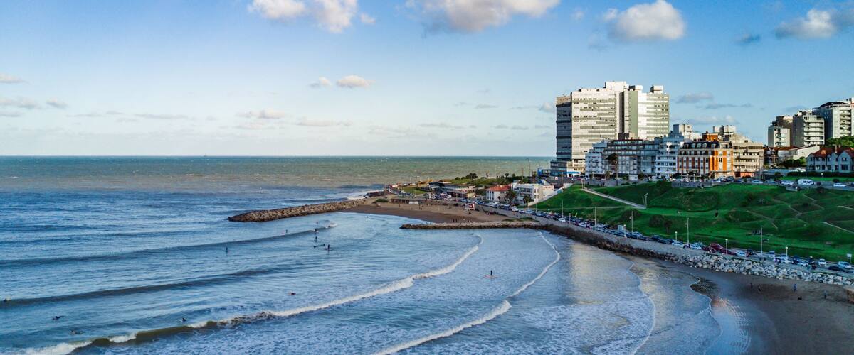 A coastal cityscape with a beach, waves, and buildings.