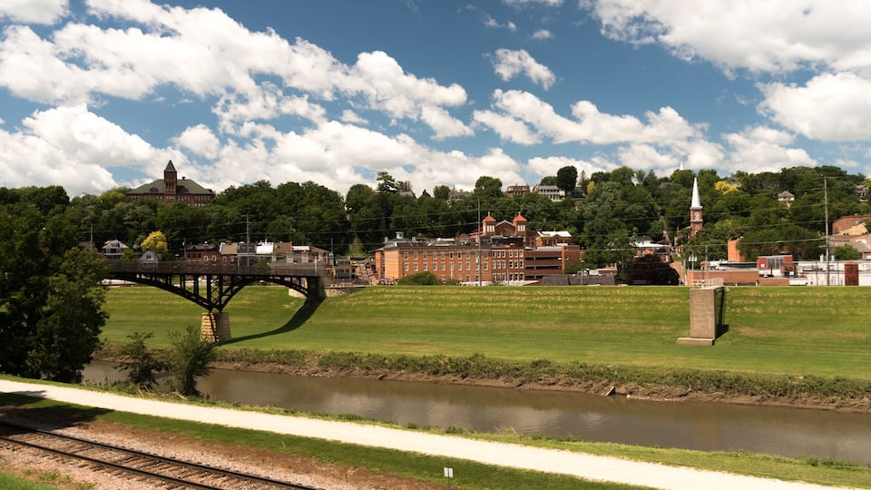 A river with a bridge, a park, and buildings in the background.