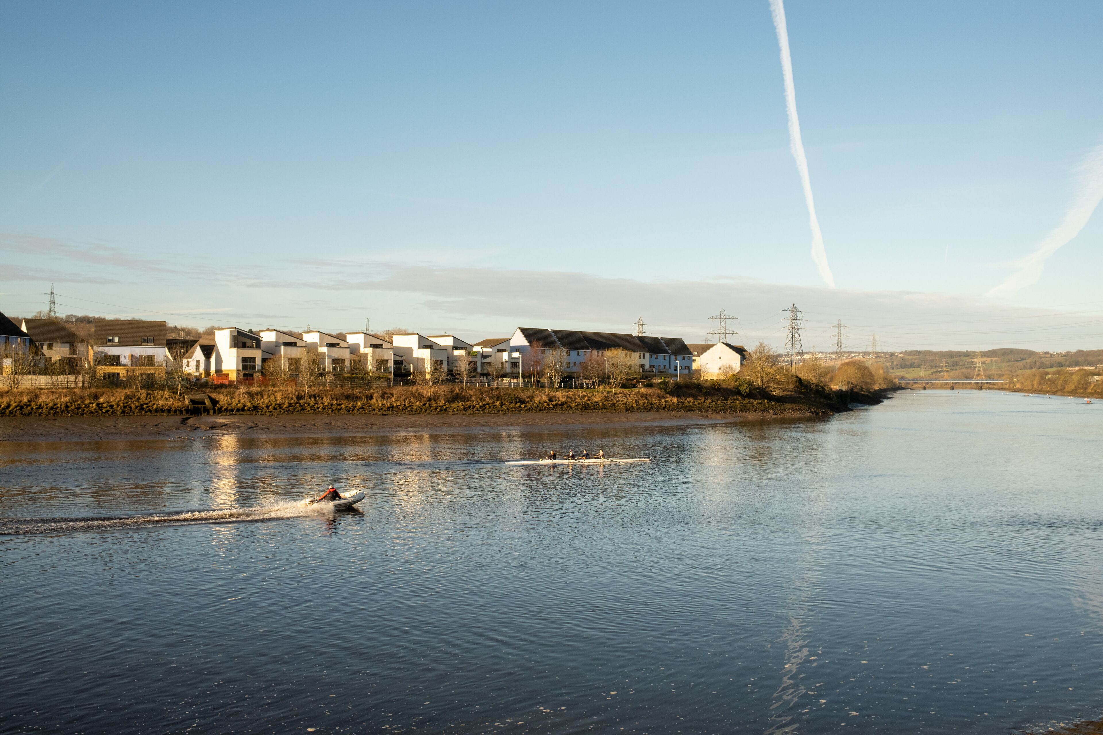 A river with houses along the bank and a boat in the water.