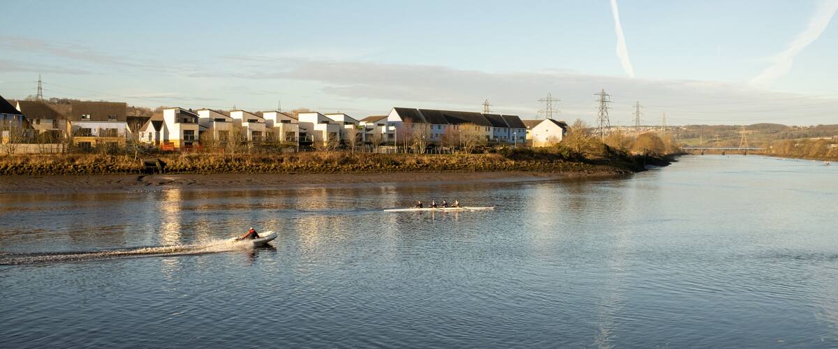 A river with houses along the bank and a boat in the water.