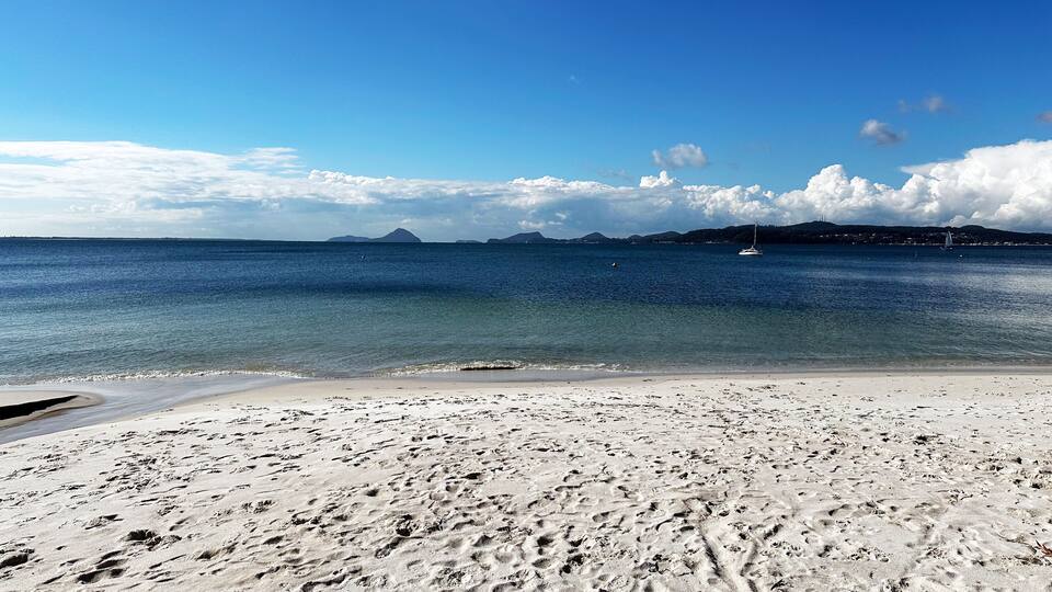 A beach with white sand and calm blue waters.
