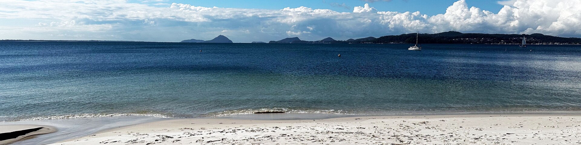 Una playa con arena blanca y aguas azules tranquilas.