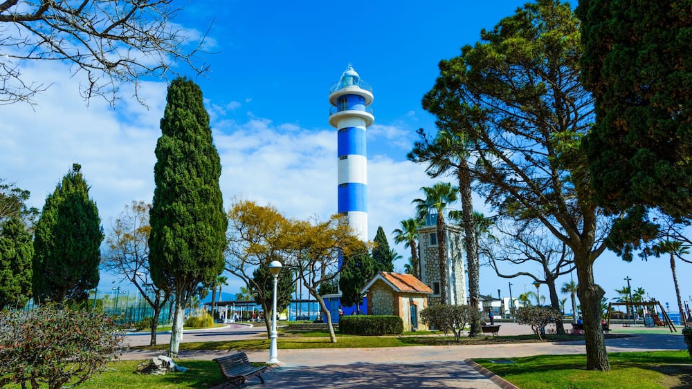 Ein Leuchtturm, ein Park mit Bänken und ein strahlend blauer Himmel.
