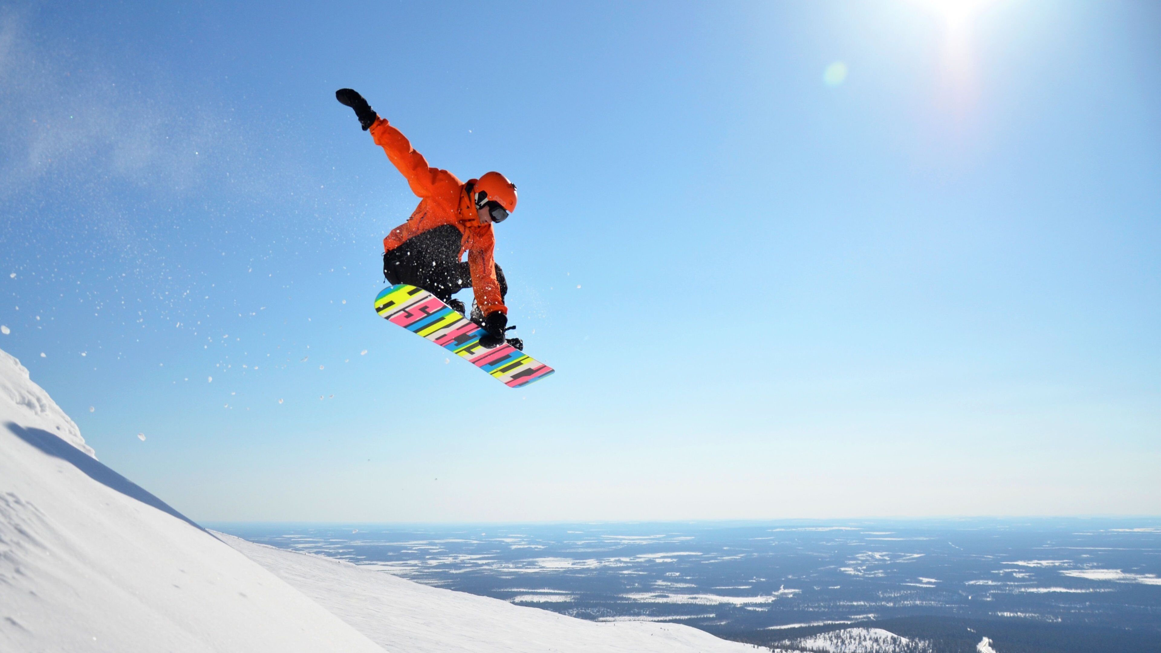 A snowboarder in mid-air against a clear blue sky.