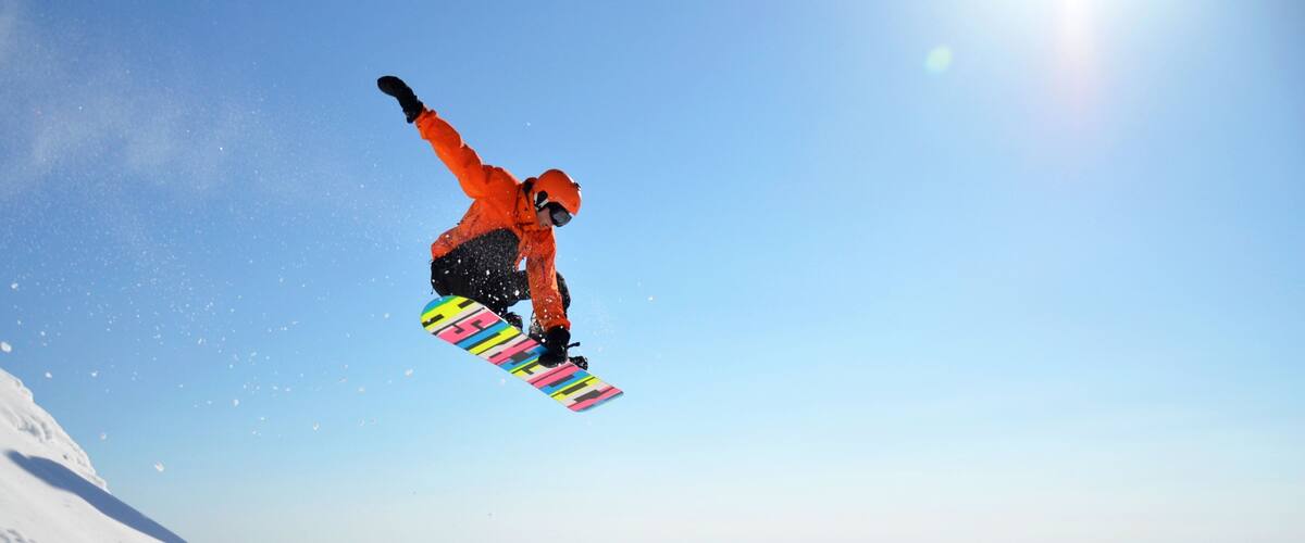 A snowboarder in mid-air against a clear blue sky.